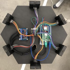 Top view of EMMA’s sensing and control system. Six distance sensors are distributed around the hexagonal structure and connected to the embedded audio and control electronics at the center, forming the technical basis for EMMA’s distributed six-voice interaction model.